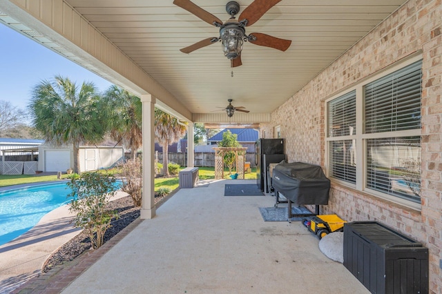 view of patio with a storage unit, an outbuilding, area for grilling, a fenced backyard, and a fenced in pool