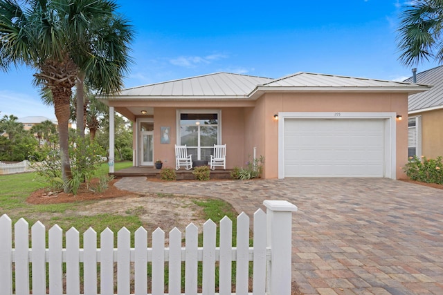 single story home featuring a garage, a porch, a fenced front yard, and stucco siding