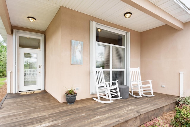 entrance to property featuring covered porch and stucco siding