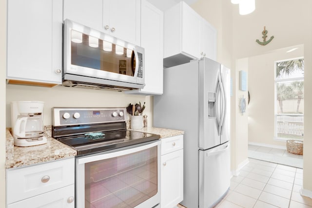 kitchen featuring light stone countertops, white cabinetry, appliances with stainless steel finishes, and light tile patterned flooring