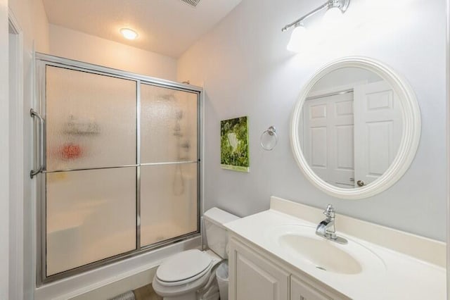 bathroom with toilet, vanity, and a shower with shower door