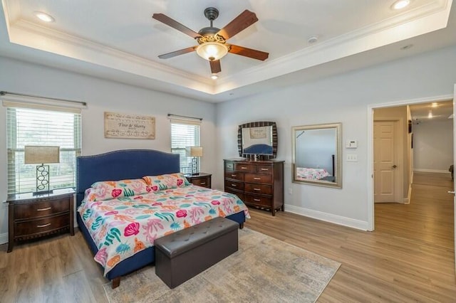 bedroom with a raised ceiling, light wood-type flooring, and ornamental molding