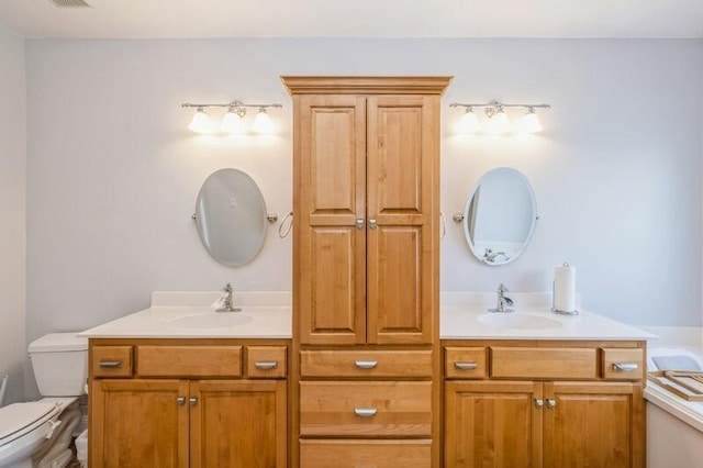 bathroom with double vanity, toilet, and a sink