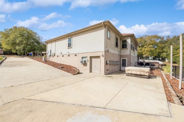 view of side of property with cooling unit, driveway, an attached garage, and fence