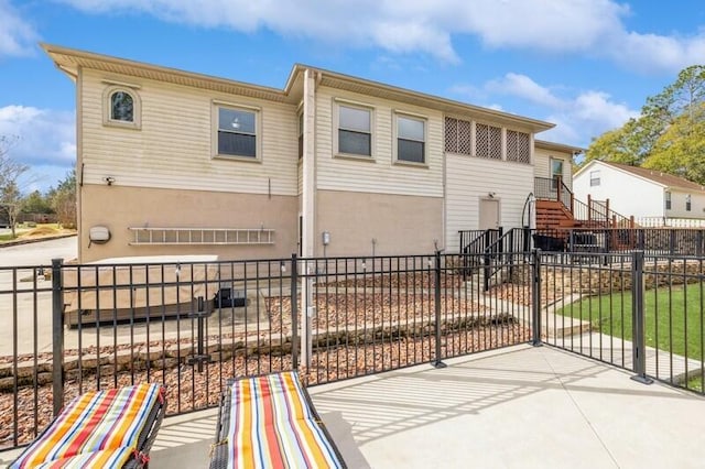 rear view of house with a fenced front yard and stairway