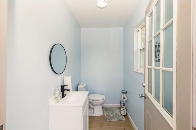 bathroom with vanity, toilet, wood finished floors, and baseboards