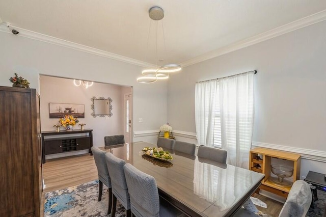 dining space with a notable chandelier, wood finished floors, and crown molding