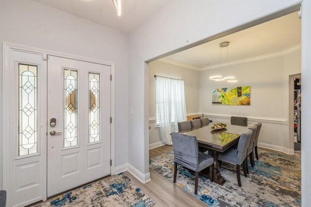 foyer entrance with ornamental molding, baseboards, an inviting chandelier, and wood finished floors