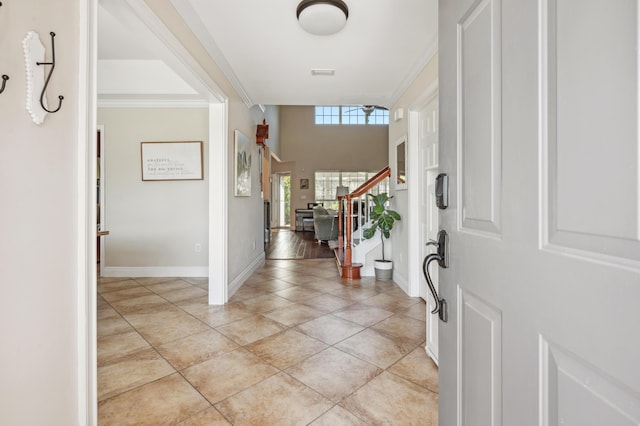 foyer featuring light tile patterned floors, stairs, baseboards, and ornamental molding