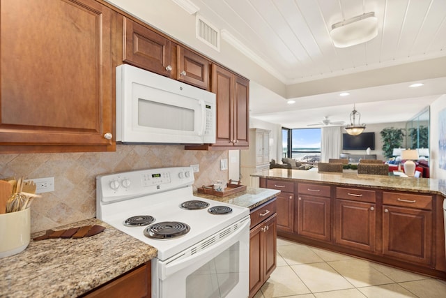 kitchen featuring tasteful backsplash, visible vents, a tray ceiling, light tile patterned floors, and white appliances