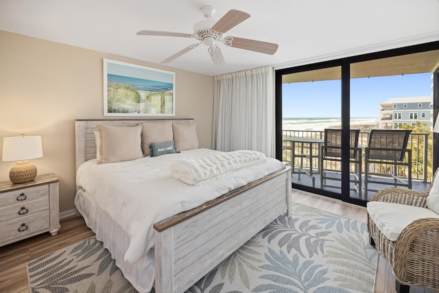 bedroom featuring floor to ceiling windows, wood finished floors, ceiling fan, and access to outside