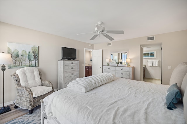 bedroom with visible vents, light wood-style flooring, ensuite bathroom, and a ceiling fan