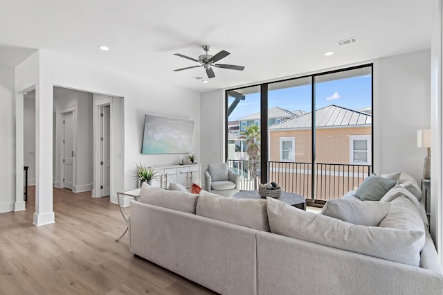 living area featuring expansive windows, recessed lighting, visible vents, and light wood-type flooring