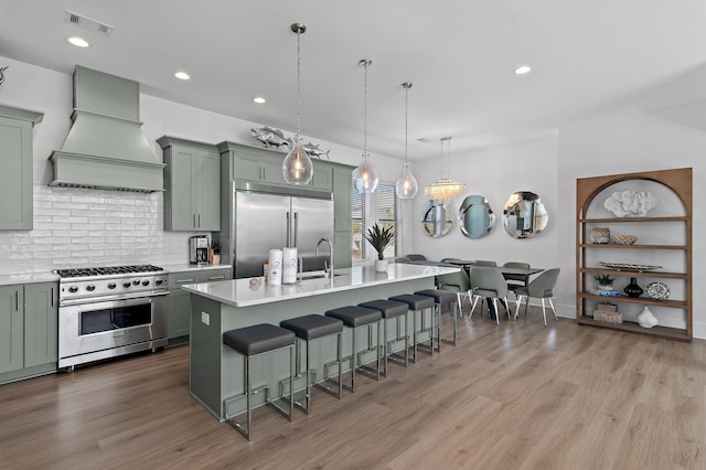 kitchen with visible vents, a kitchen bar, custom range hood, light countertops, and high end appliances