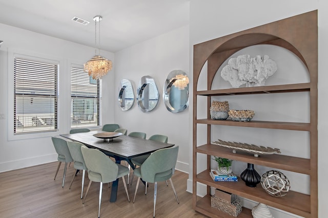 dining room with a notable chandelier, wood finished floors, visible vents, and baseboards