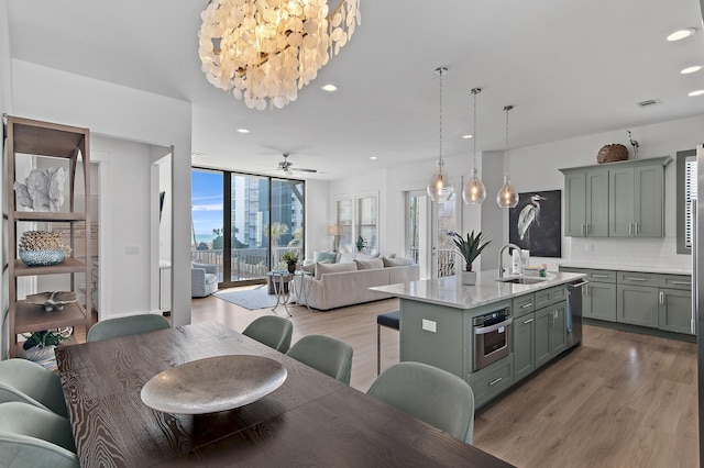 kitchen featuring tasteful backsplash, an island with sink, light wood-style flooring, appliances with stainless steel finishes, and a sink