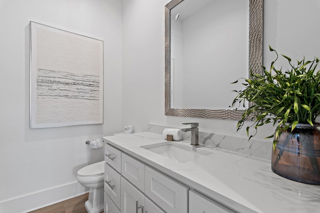 bathroom with baseboards, toilet, wood finished floors, and vanity