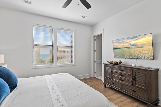 bedroom featuring ceiling fan, visible vents, baseboards, and wood finished floors