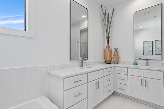 full bath featuring a sink, walk in shower, wainscoting, and double vanity