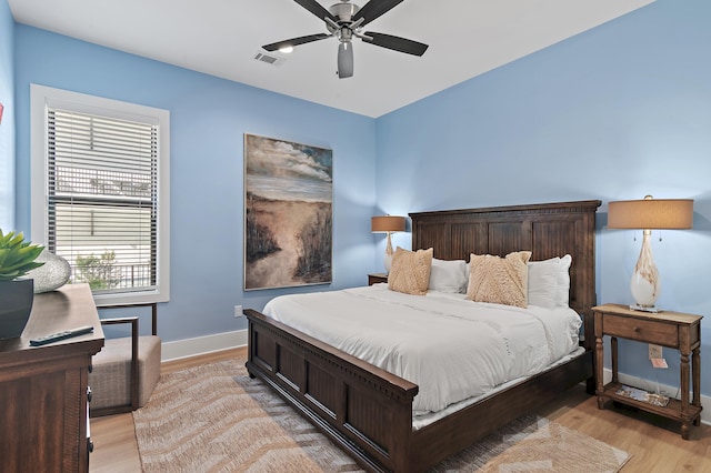 bedroom with ceiling fan, visible vents, baseboards, and light wood-style flooring