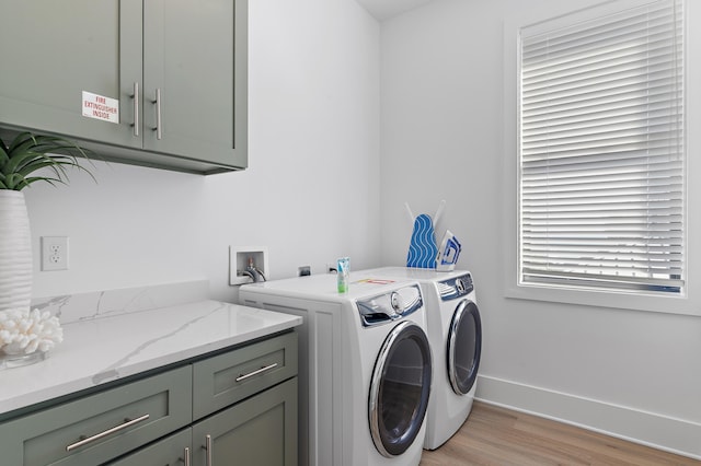 washroom with washer and dryer, light wood-style flooring, cabinet space, and baseboards