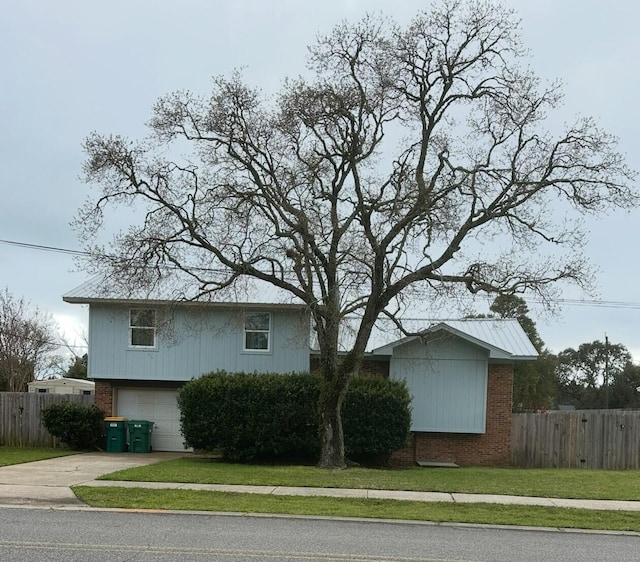 view of front of home with brick siding, driveway, a front yard, and fence