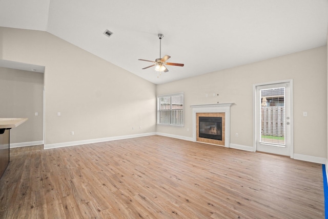 unfurnished living room with visible vents, light wood finished floors, lofted ceiling, a fireplace, and ceiling fan