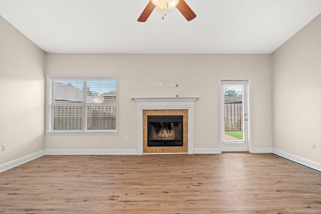 unfurnished living room featuring light wood-type flooring, baseboards, and a tiled fireplace