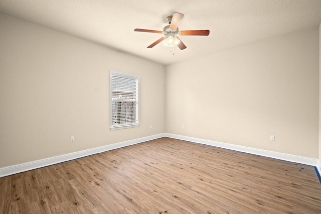 spare room featuring ceiling fan, baseboards, and wood finished floors