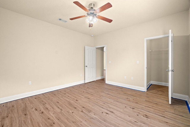 unfurnished bedroom with visible vents, light wood-style flooring, a walk in closet, and baseboards