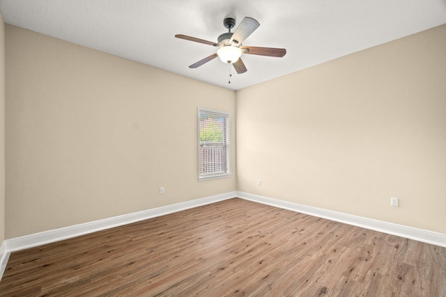 spare room with wood finished floors, baseboards, and ceiling fan