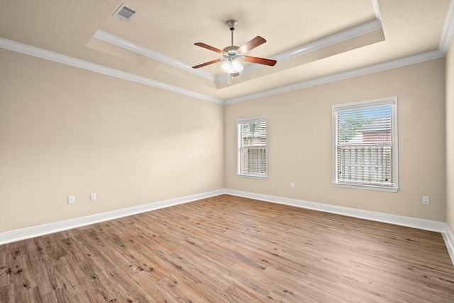 empty room with a tray ceiling, visible vents, and wood finished floors