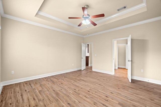 unfurnished room featuring a tray ceiling, baseboards, visible vents, and light wood-style flooring