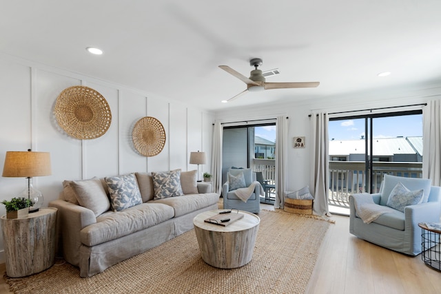 living room with light wood finished floors, a decorative wall, recessed lighting, and a ceiling fan