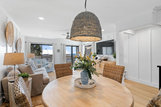 dining space with recessed lighting, light wood-style flooring, crown molding, and a decorative wall