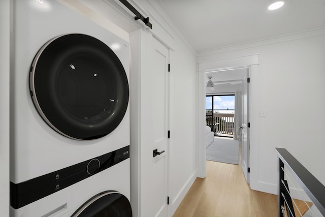 laundry room featuring laundry area, light wood-style flooring, crown molding, and stacked washer and dryer