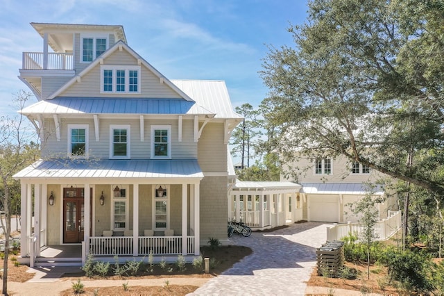 view of front of house featuring covered porch, metal roof, decorative driveway, a balcony, and a standing seam roof