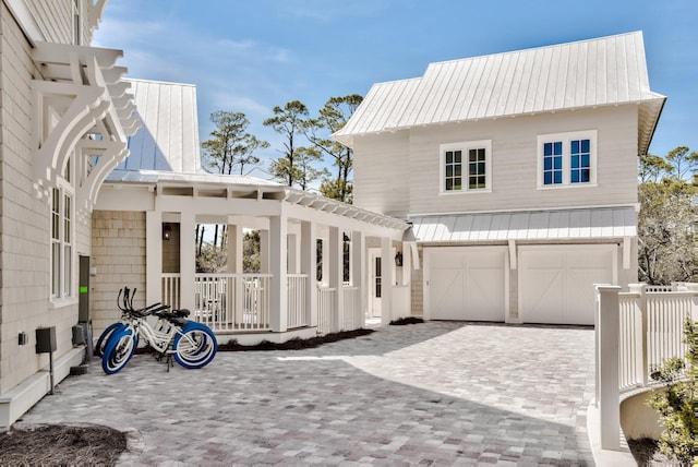 view of property exterior with decorative driveway, metal roof, an attached garage, and a standing seam roof