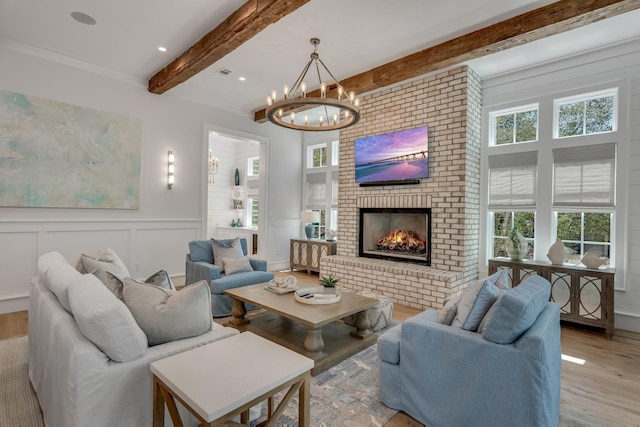 living area featuring beam ceiling, plenty of natural light, a brick fireplace, and wood finished floors