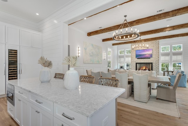 kitchen featuring beam ceiling, visible vents, light wood-type flooring, and a wealth of natural light