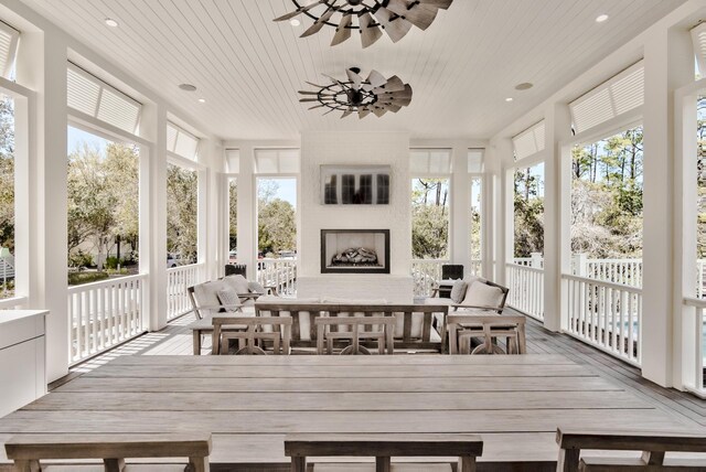 sunroom / solarium with wooden ceiling, a large fireplace, and ceiling fan