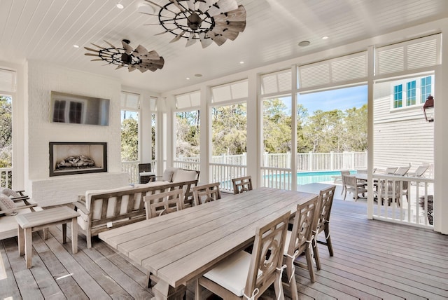 sunroom / solarium with a wealth of natural light, wood ceiling, and a ceiling fan