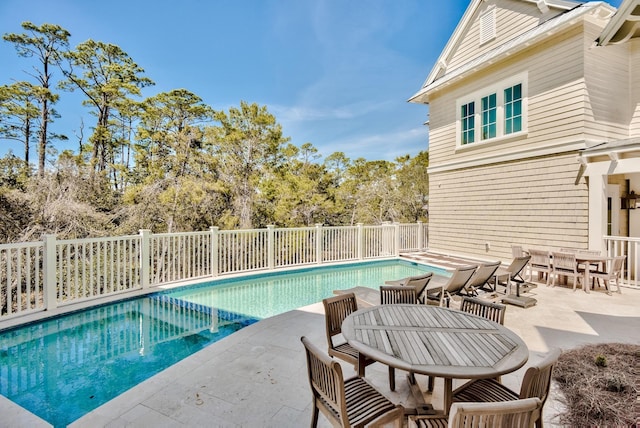 view of swimming pool with a fenced in pool, fence, outdoor dining space, and a patio area