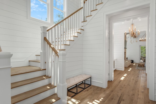 stairs featuring wooden walls, wood finished floors, and a chandelier