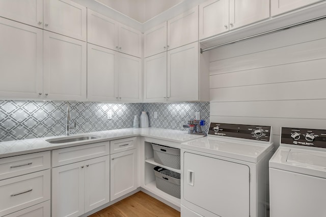 washroom featuring cabinet space, separate washer and dryer, light wood-style floors, and a sink