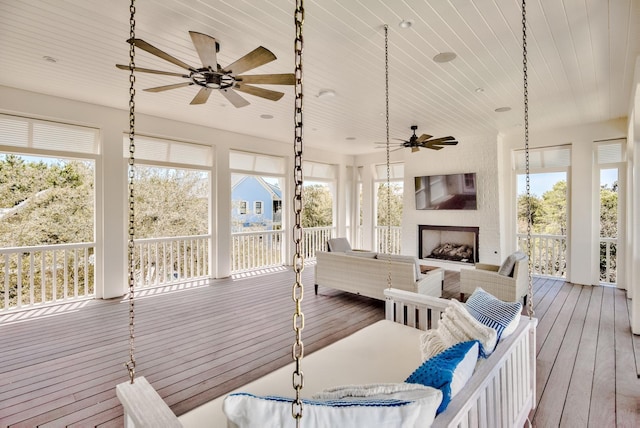 sunroom / solarium with wood ceiling, a fireplace, and ceiling fan