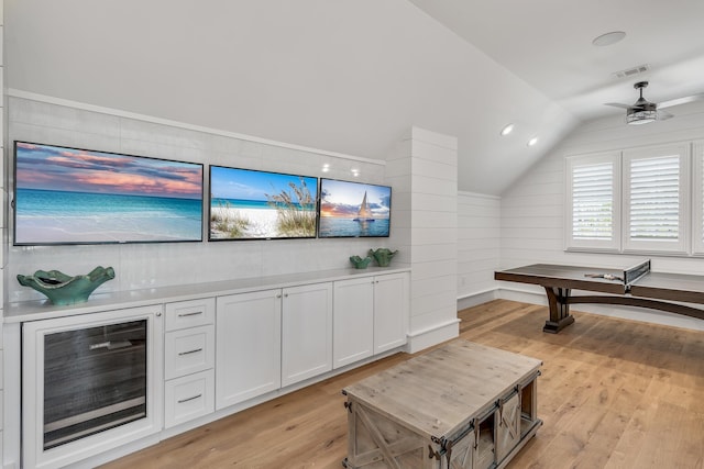 playroom featuring vaulted ceiling, beverage cooler, light wood-style floors, and visible vents