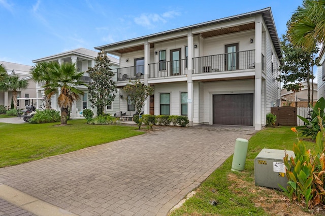 view of front of home with fence, a front yard, decorative driveway, a garage, and a balcony