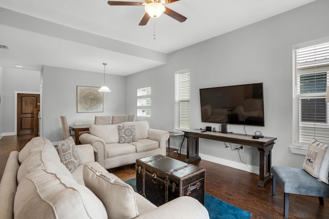 living area with visible vents, a ceiling fan, baseboards, and wood finished floors