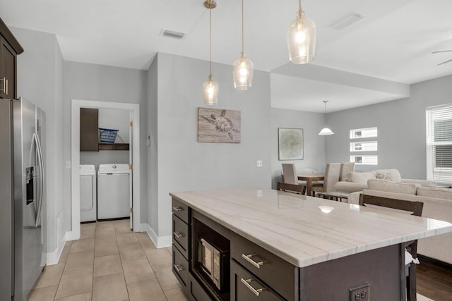 kitchen featuring washer and dryer, visible vents, stainless steel fridge, and dark brown cabinets